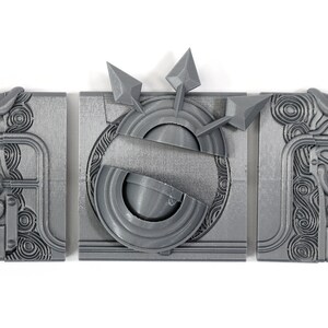 May include: Three gray 3D printed pieces of a puzzle, each with intricate designs. The center piece features a circular design with three arrows pointing outwards.