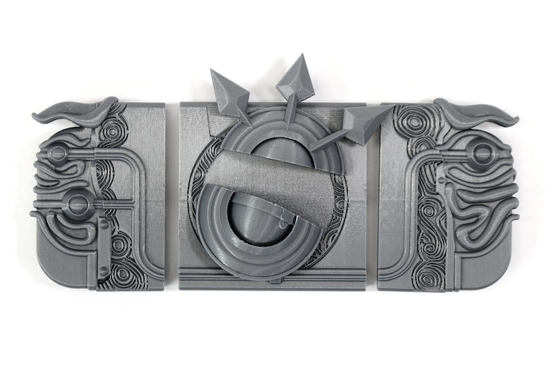 May include: Three gray 3D printed pieces of a puzzle, each with intricate designs. The center piece features a circular design with three arrows pointing outwards.