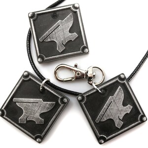 May include: Three silver-colored metal pendants with an anvil design. The pendants are attached to black cords and one has a silver-colored clasp.