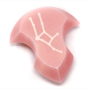 Op de afbeelding: Een roze, onregelmatig gevormde, keramische hanger met een wit sterrenbeeld ontwerp.