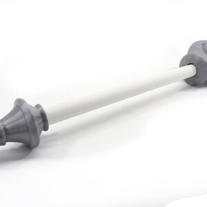K&ouml;nnte beinhalten: Eine dekorative Gardinenstange mit grauen Endst&uuml;cken und einer wei&szlig;en Stange. Die Endst&uuml;cke haben ein detailliertes, verziertes Design. Die Stange ist etwa 76 cm lang.