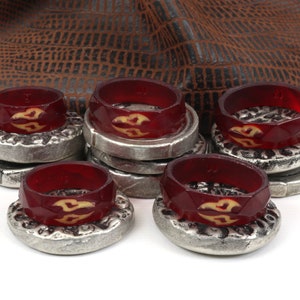 May include: A set of eight red and silver game pieces with a stylized flame design. The pieces are stacked and arranged on a white surface.