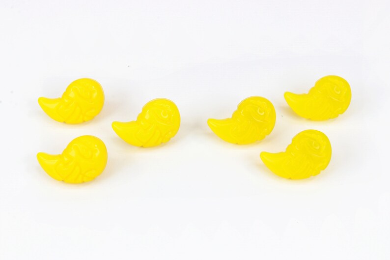 K&ouml;nnte beinhalten: Sechs gelbe Plastikkn&ouml;pfe in Vogelform mit einem Wirbelmuster.