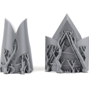 May include: Two gray 3D printed crown-shaped objects with intricate designs. The crowns are made of a textured material and have a detailed pattern of branches and leaves.