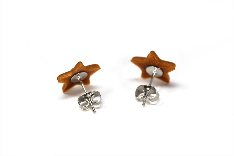 May include: A pair of gold star-shaped earrings with silver posts and backs.