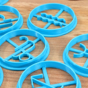 May include: A set of blue plastic cookie cutters shaped like astrological signs. The signs include Libra, Aquarius, Pisces, Sagittarius, and Capricorn.