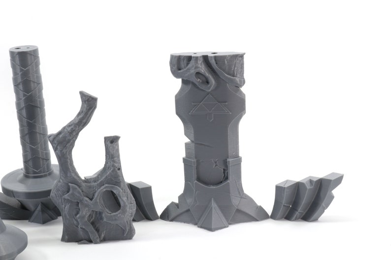 May include: A set of five gray 3D printed miniature dungeon pieces, including a pillar with a triangular symbol, a broken pillar, a tree stump, and two smaller pieces.