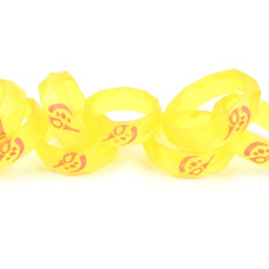 May include: A set of six yellow rubber rings with a red design. The rings are stacked on top of each other.