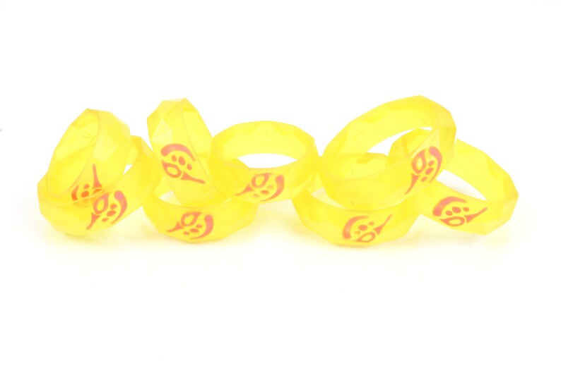 May include: A set of six yellow rubber rings with a red design. The rings are stacked on top of each other.