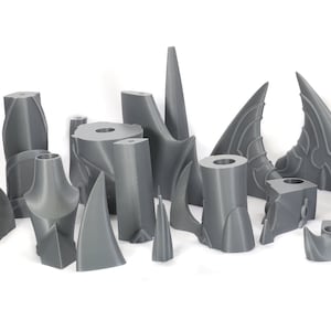 Peut inclure: Une collection de pi&egrave;ces en plastique gris imprim&eacute;es en 3D, certaines avec des motifs complexes, ressemblant &agrave; des &eacute;l&eacute;ments architecturaux ou &agrave; des parties d'un mod&egrave;le.