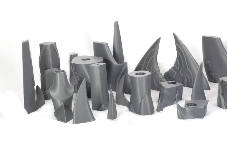 Peut inclure: Une collection de pi&egrave;ces en plastique gris imprim&eacute;es en 3D, certaines avec des motifs complexes, ressemblant &agrave; des &eacute;l&eacute;ments architecturaux ou &agrave; des parties d'un mod&egrave;le.