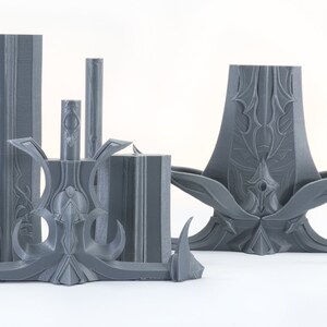Puede incluir: Un conjunto de cinco piezas impresas en 3D de color gris con dise&ntilde;os intrincados. Las piezas est&aacute;n hechas de pl&aacute;stico y tienen un acabado liso y mate.