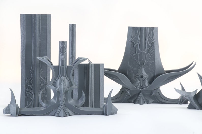 Puede incluir: Un conjunto de cinco piezas impresas en 3D de color gris con dise&ntilde;os intrincados. Las piezas est&aacute;n hechas de pl&aacute;stico y tienen un acabado liso y mate.