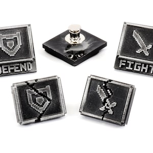 May include: Five silver-colored metal game pieces with pixelated graphics. Two pieces feature a sword, two pieces feature a shield, and one piece features a base with a silver-colored top. The pieces have the words "FIGHT" and "DEFEND" printed on them.