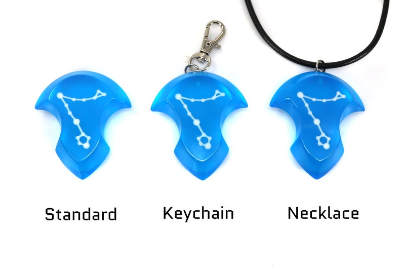 K&ouml;nnte beinhalten: Drei Versionen eines blauen Anh&auml;ngers mit einem wei&szlig;en Sternbild-Design. Der Anh&auml;nger ist als Standardst&uuml;ck, als Schl&uuml;sselanh&auml;nger und als Halskette erh&auml;ltlich.
