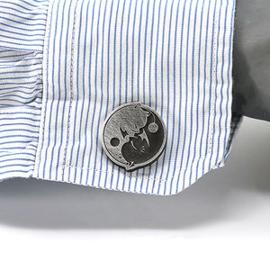 May include: A pair of silver cufflinks with a black and white yin yang design.