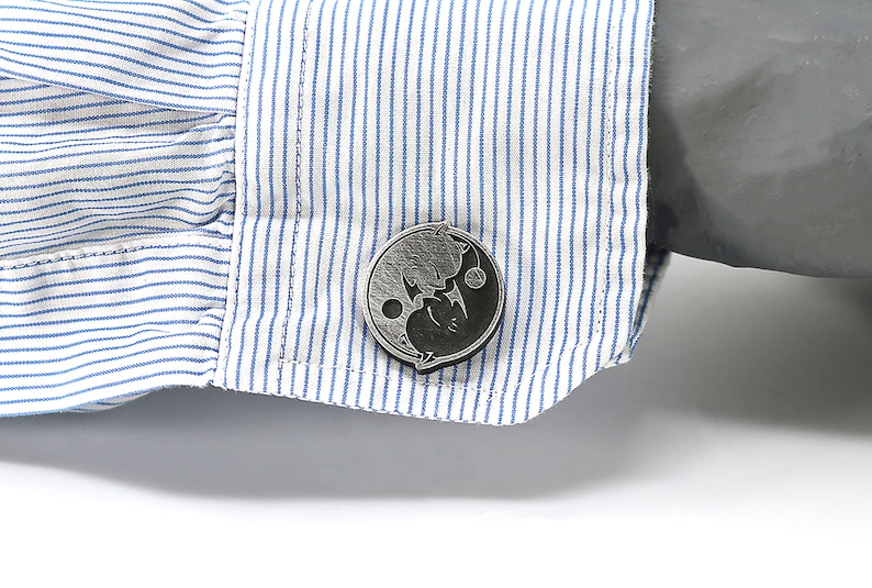 May include: A pair of silver cufflinks with a black and white yin yang design.