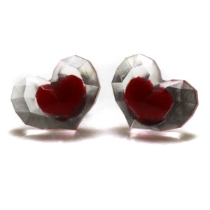 Puede incluir: Un par de pendientes en forma de coraz&oacute;n con un dise&ntilde;o transparente facetado. Cada pendiente tiene un coraz&oacute;n rojo en el interior.