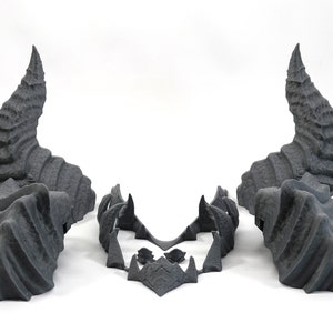 May include: A set of three gray 3D printed horns, two large horns and a smaller piece that connects them. The horns are detailed with a textured, scaly surface.