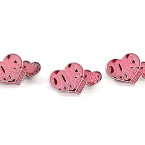 May include: Three pink heart-shaped pins with the text "DOKI DOKI CLUB" on them.