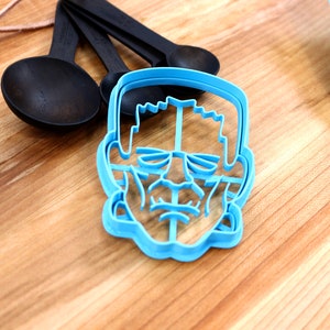May include: Blue plastic cookie cutter shaped like a Frankenstein's monster face.