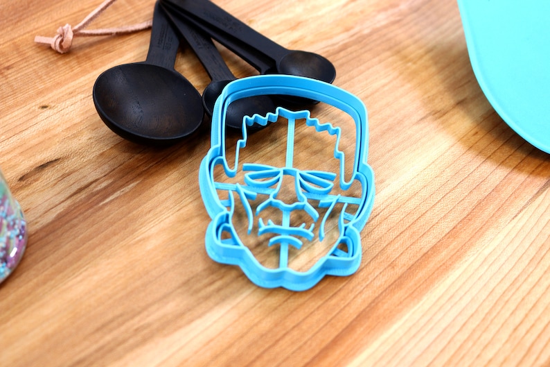 May include: Blue plastic cookie cutter shaped like a Frankenstein's monster face.