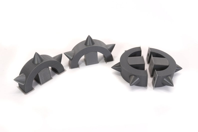 May include: Three grey plastic pieces with spikes, each shaped like a half-circle, designed to be assembled into a circle.