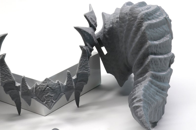 May include: Two 3D printed gray plastic dragon head sculptures. One is a full head and the other is a smaller, more detailed head.
