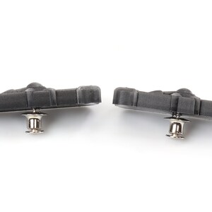 May include: Two black brake pads with silver metal pins. The brake pads are designed for bicycles.