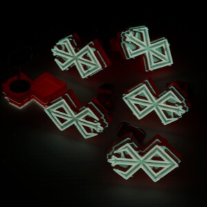 Puede incluir: Seis adornos blancos, geom&eacute;tricos, en forma de estrella con un contorno rojo. Los adornos est&aacute;n dispuestos en un grupo sobre un fondo negro.