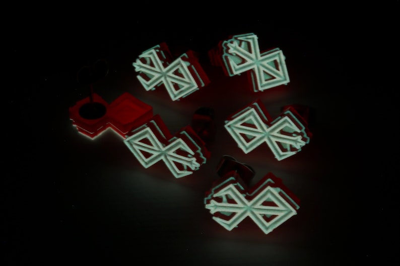 Puede incluir: Seis adornos blancos, geom&eacute;tricos, en forma de estrella con un contorno rojo. Los adornos est&aacute;n dispuestos en un grupo sobre un fondo negro.