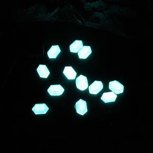 K&ouml;nnte beinhalten: Eine Streuung kleiner, blaugr&uuml;ner, sechseckiger Lichter auf schwarzem Hintergrund.