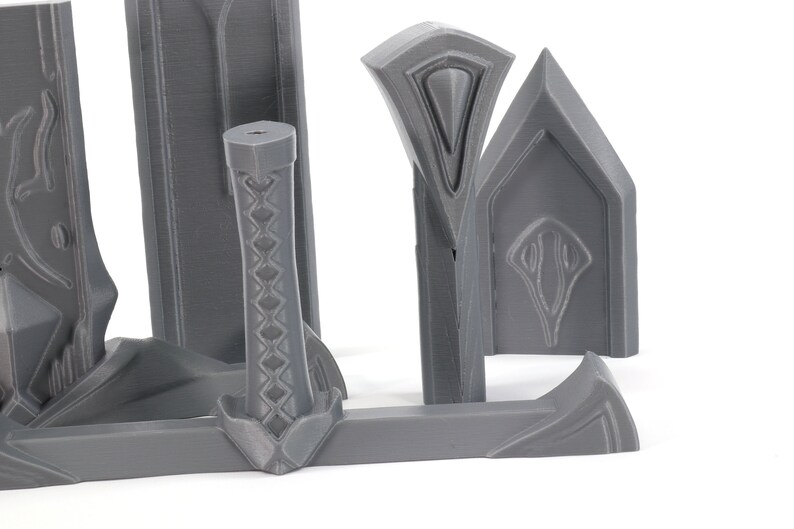 May include: A set of gray plastic sword parts for a 3D printed model. The parts include the blade, hilt, and pommel.