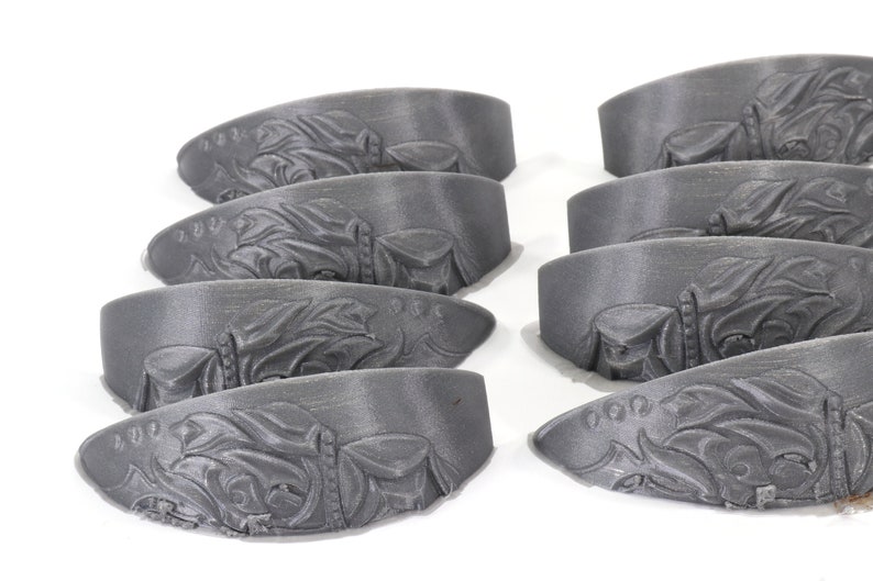 May include: Eight grey 3D printed decorative pieces with an intricate design. The pieces are shaped like a curved, flat surface.