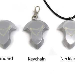 May include: Three versions of a silver-colored pendant with a white design. The pendant is available as a standard piece, a keychain, and a necklace.