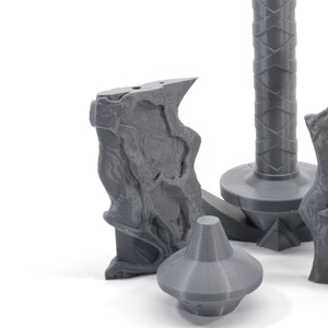 May include: A set of four gray 3D printed pieces that appear to be parts of a fantasy weapon or prop. The pieces are made of a smooth, plastic-like material and have intricate details.