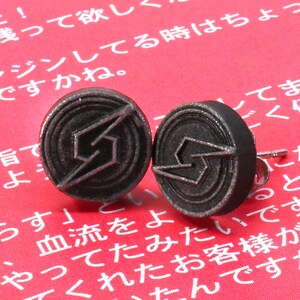 May include: A pair of silver-coloured metal earrings with a lightning bolt design. The earrings are on a red background.