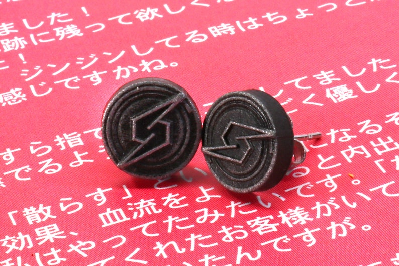 May include: A pair of silver-coloured metal earrings with a lightning bolt design. The earrings are on a red background.