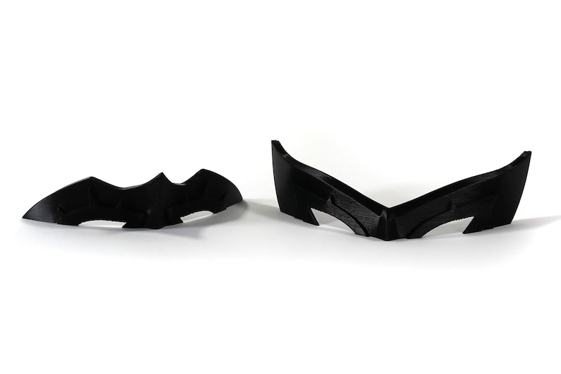 May include: Two black plastic pieces shaped like a bat, one is a full bat shape and the other is a bat wing shape.