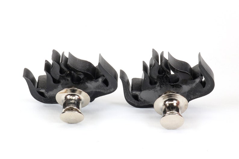 May include: Two black flame-shaped metal clasps with silver push-button closures.
