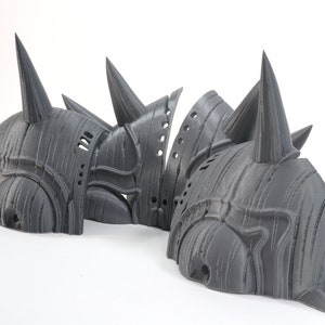 May include: Three gray 3D printed helmets with spikes. The helmets are made of a textured material and have a detailed design.