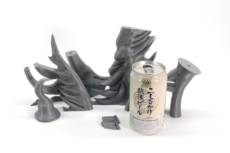 May include: A set of 3D printed gray plastic dragon wings, a can of Japanese beer, and a set of small gray metal rods.