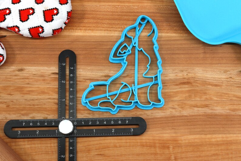 K&ouml;nnte beinhalten: Ein blauer Plastik-Ausstecher in Form eines heulenden Wolfes. Der Ausstecher liegt auf einer Holzoberfl&auml;che mit einem Lineal und einem Nudelholz.