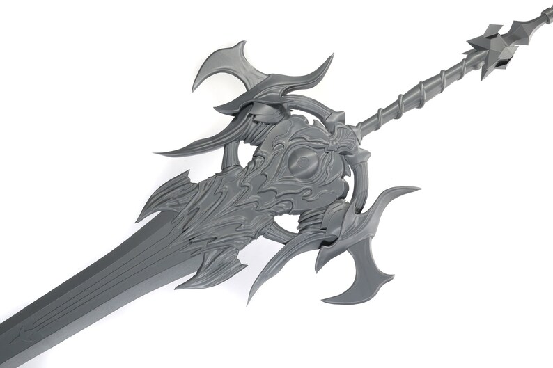 May include: A gray, intricately detailed sword with a long, sharp blade and a decorative, ornate hilt. The hilt features a circular design with a central eye-like motif and multiple pointed protrusions.