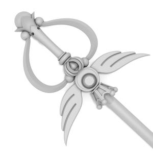May include: A white, ornate wand with a heart-shaped loop, wings, and a crown-like tip. The wand is made of a smooth, shiny material.