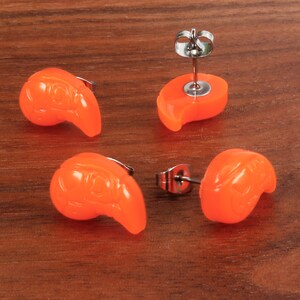 May include: Four pairs of orange stud earrings with a teardrop shape. The earrings have a silver post and butterfly backing.