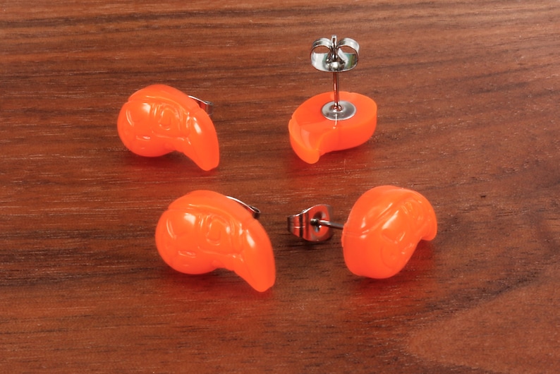 May include: Four pairs of orange stud earrings with a teardrop shape. The earrings have a silver post and butterfly backing.