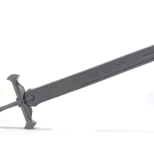 May include: A gray metal sword with intricate designs on the blade. The sword has a cross-shaped guard and a pointed tip.