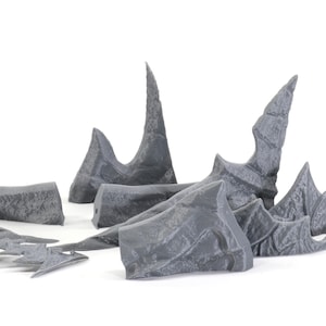 May include: A set of grey 3D printed plastic pieces shaped like jagged rock formations. These pieces can be used for tabletop gaming or model building.