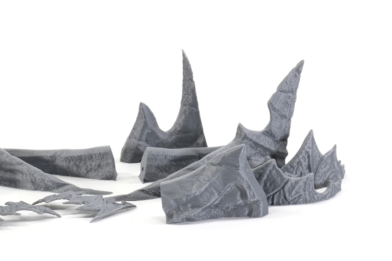 May include: A set of grey 3D printed plastic pieces shaped like jagged rock formations. These pieces can be used for tabletop gaming or model building.